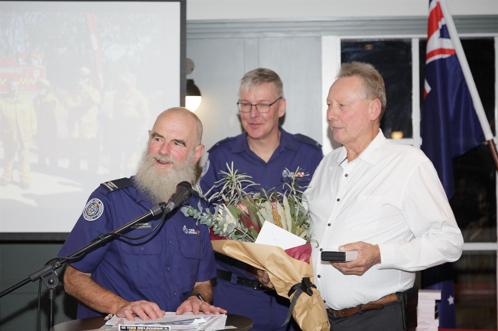 Fred Kober receiving his 60-year medal of service from Captain Michael Scroggie and MC Peter Mildenhall